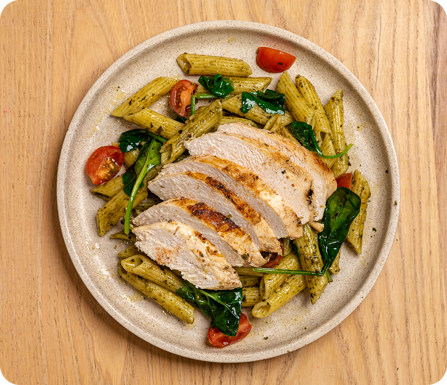 Plated dish of pasta with chicken and vegetables on a wooden surface