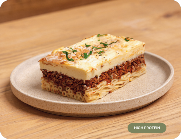 Layered pasta dish on a plate with 'High Protein' label on a wooden surface