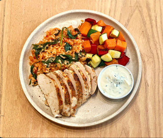 Plated meal with rice, chicken, and vegetables on a wooden surface