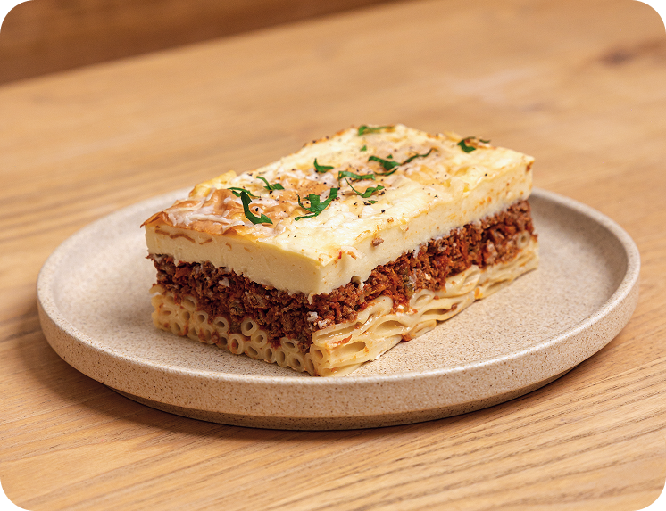 Layered pasta dish on a beige plate with a wooden background