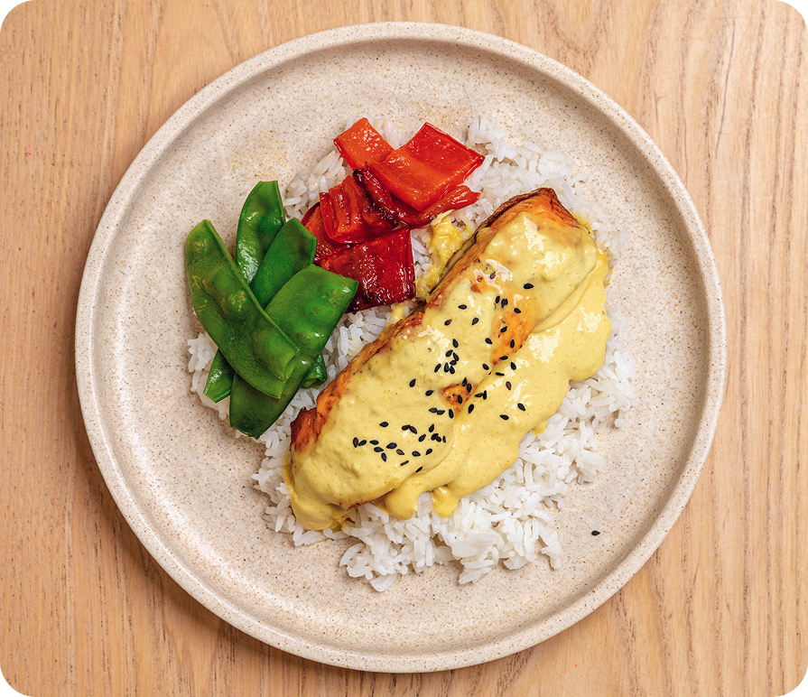 Plate of food with rice, fish, and vegetables on a wooden surface