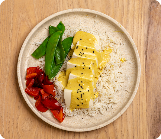 Plate of food with yellow dish, rice, and vegetables on a wooden surface